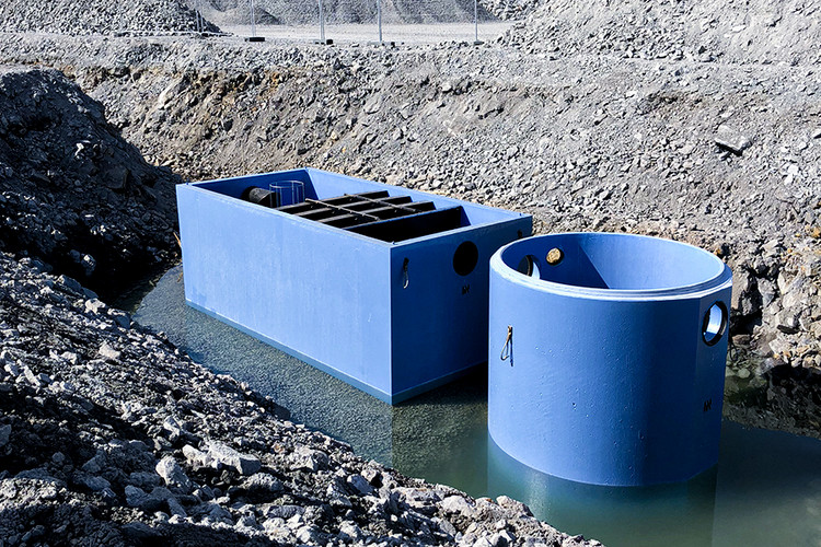 Blå rektangulära och runda betongtankar i vatten.