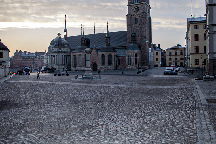 Stenbelagt torg framför pampig byggnad med klocktorn.