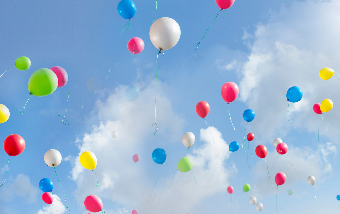 Blå himmel och vita moln med en massa ballonger i olika färger.