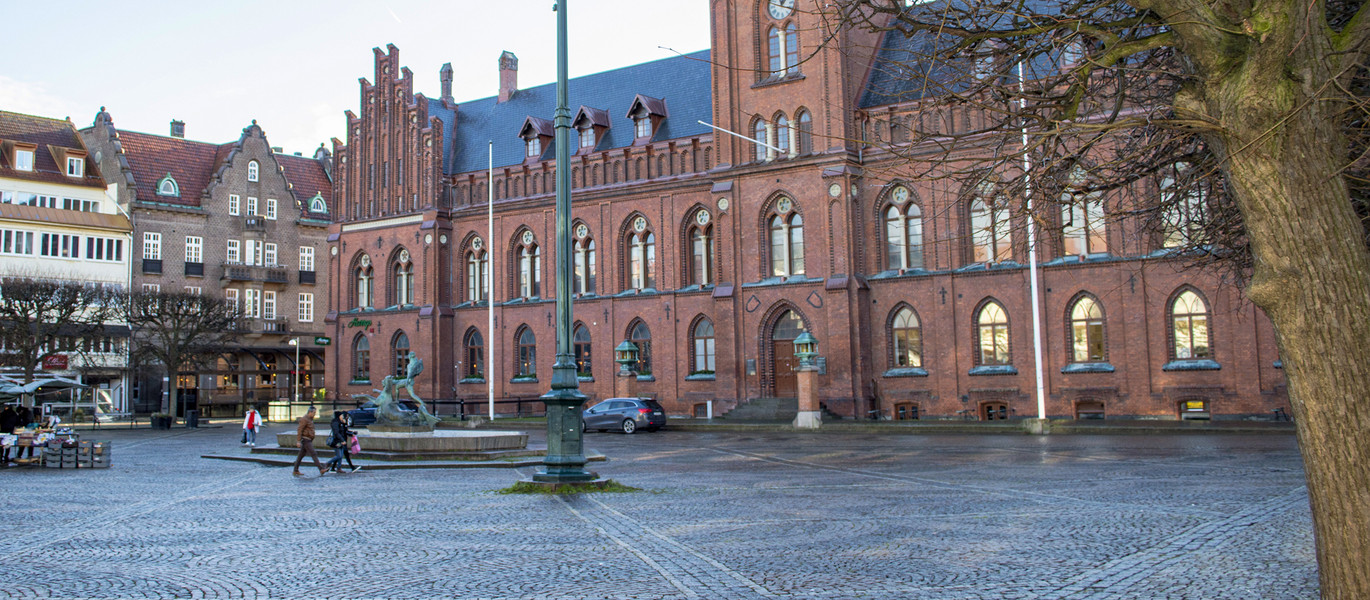 Ett torg med en stor byggnad med ett klocktorn i bakgrunden.