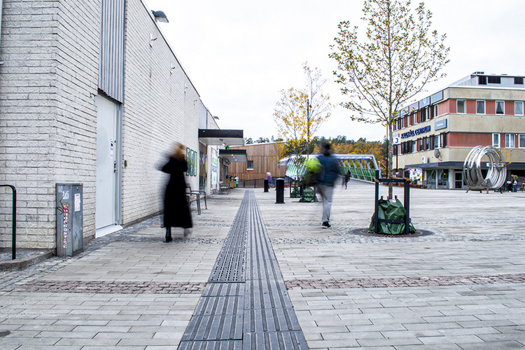 En kvinna går på torget med en man som går snett bakom henne.