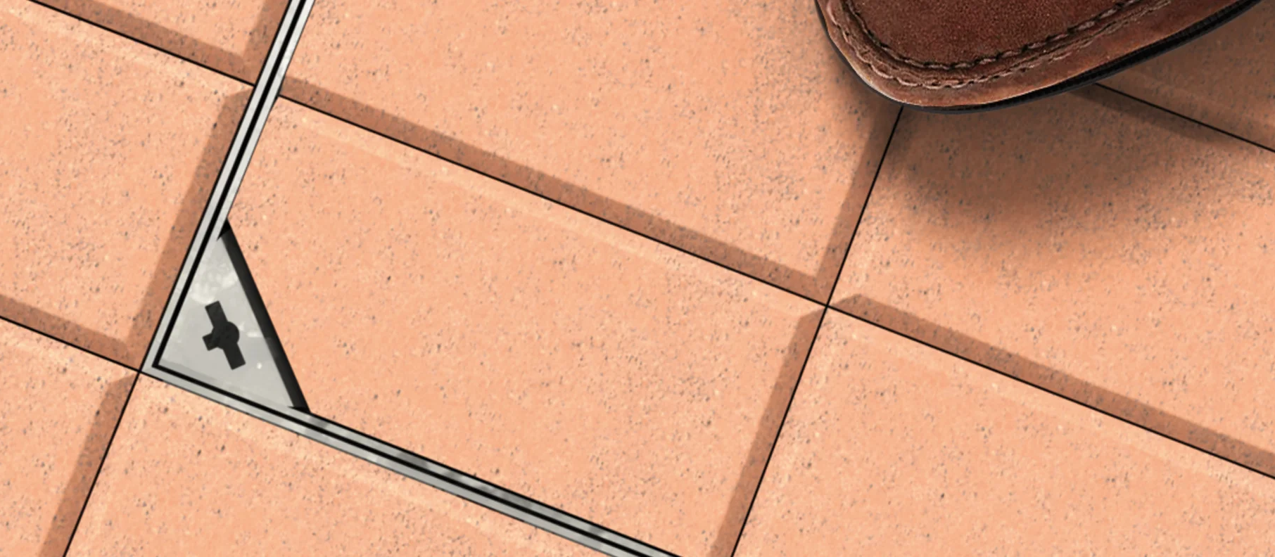 Terrakottafärgade golvplattor med lucka samt brun sko.