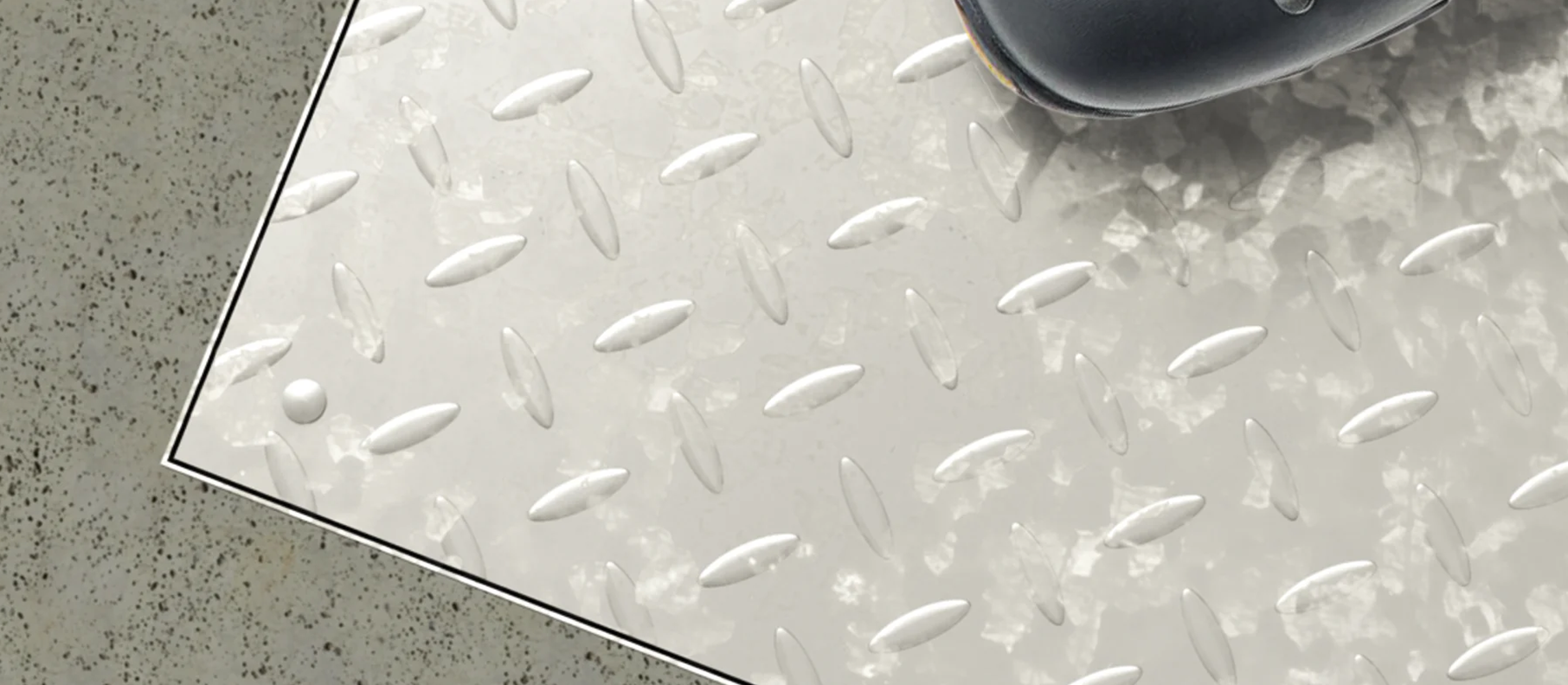 Metallfärgad golvlucka på prickigt golv.