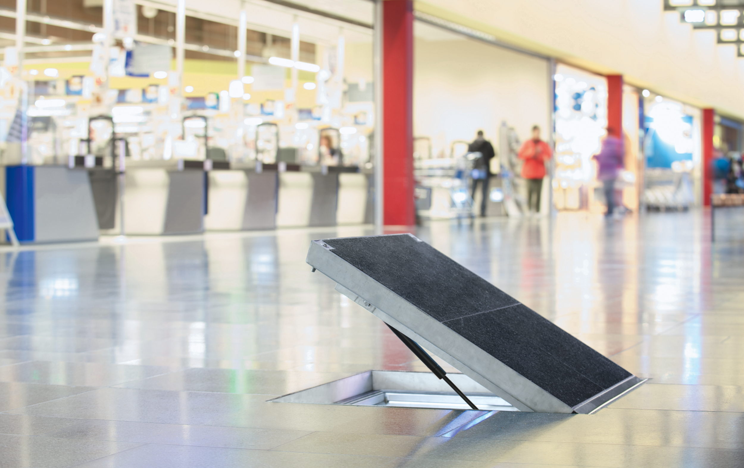 Halvt öppen golvlucka med svart ovandel.